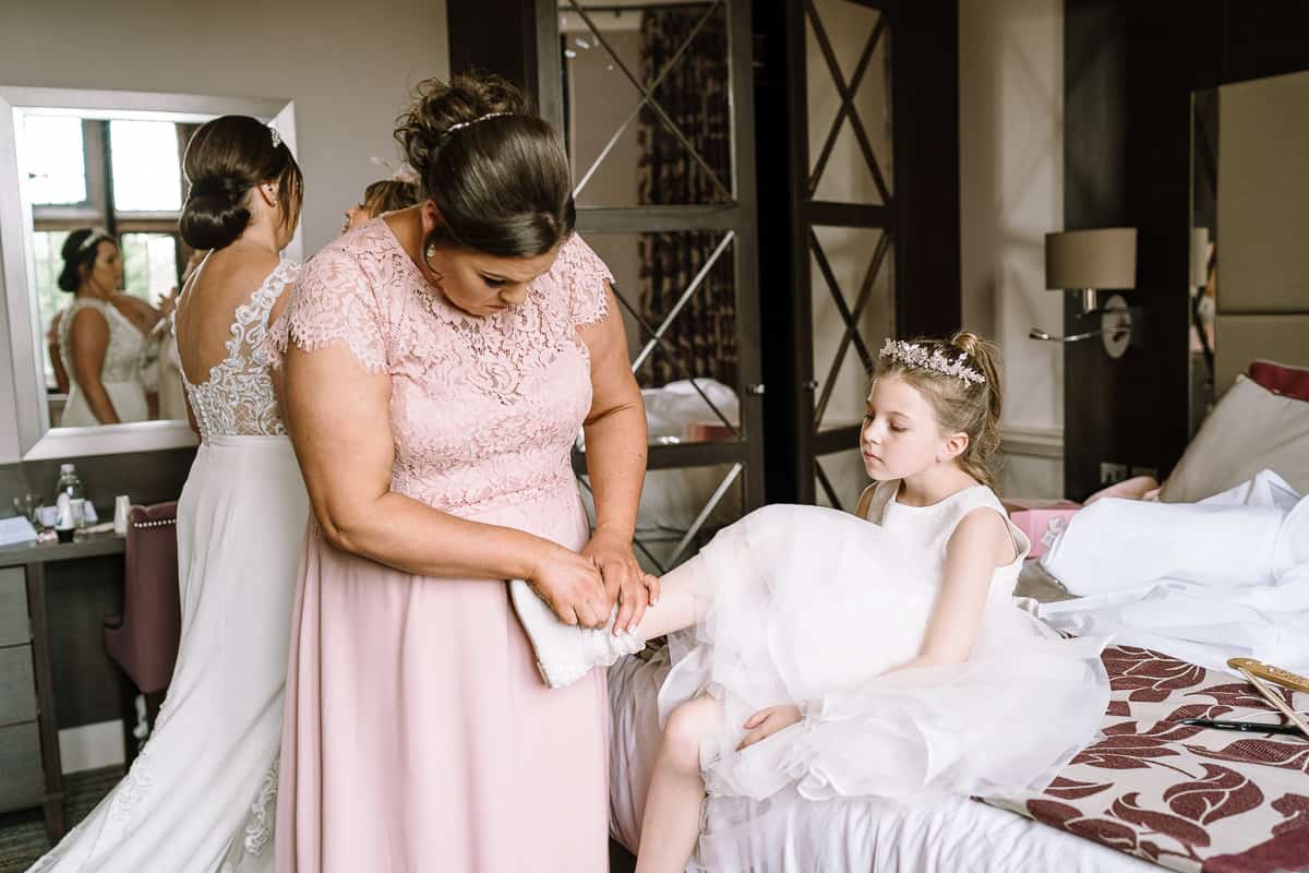Flower girl having her shoes put on prior to the wedding ceremony at Abbey House Hotel, Barrow in Furness