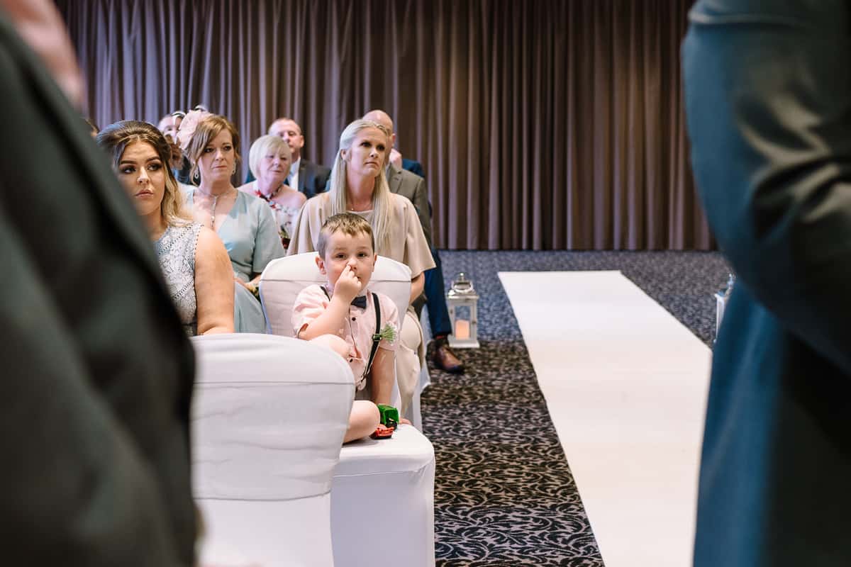 Little boy waiting for the wedding ceremony to start at Abbey House Hotel, Barrow in Furness