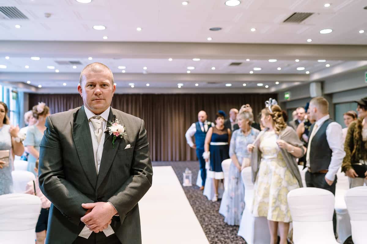 Nervous groom waiting for the wedding ceremony to start in the Cavendish Suite at Abbey House Hotel, Barrow in Furness 