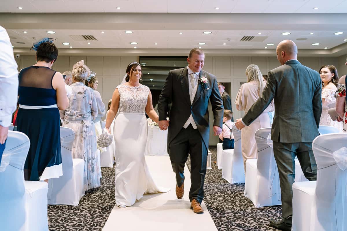 Walking down the aisle the wedding ceremony in the Cavendish Suite at Abbey House Hotel, Barrow-in-Furness