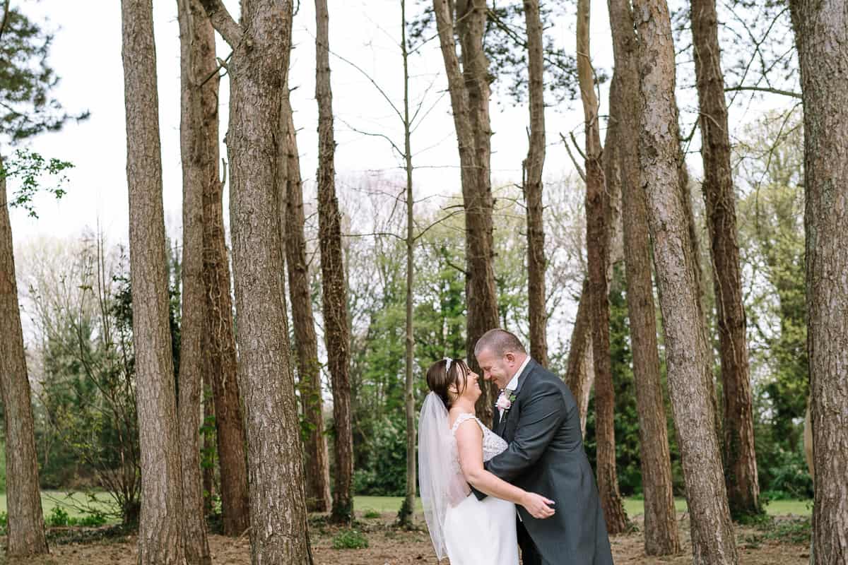 Bride and groom embracing in the woods on the grounds of Abbey House Hotel on their wedding day