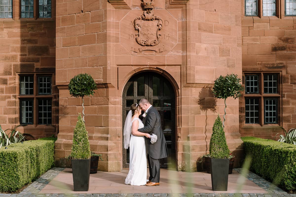Bride and groom embracing in front of Abbey House Hotel main door