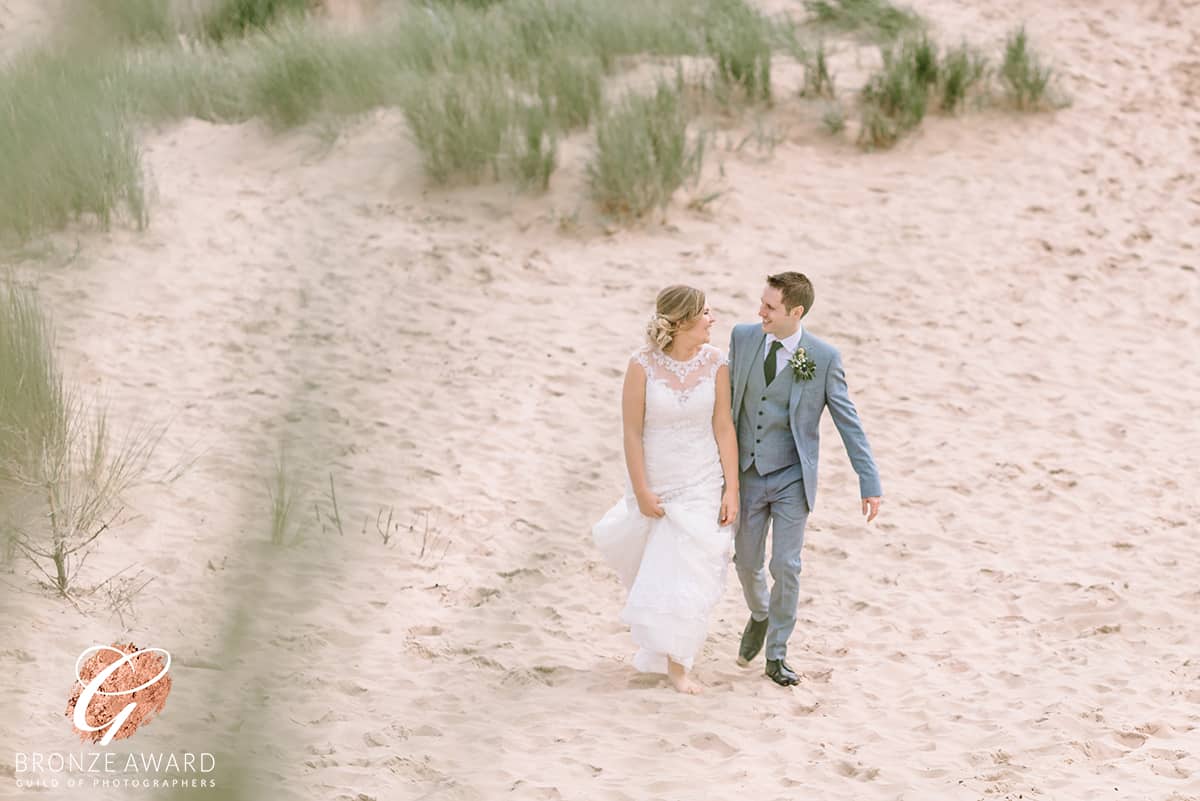 Bride and Groom walking on the sand dunes at Formby, Merseyside