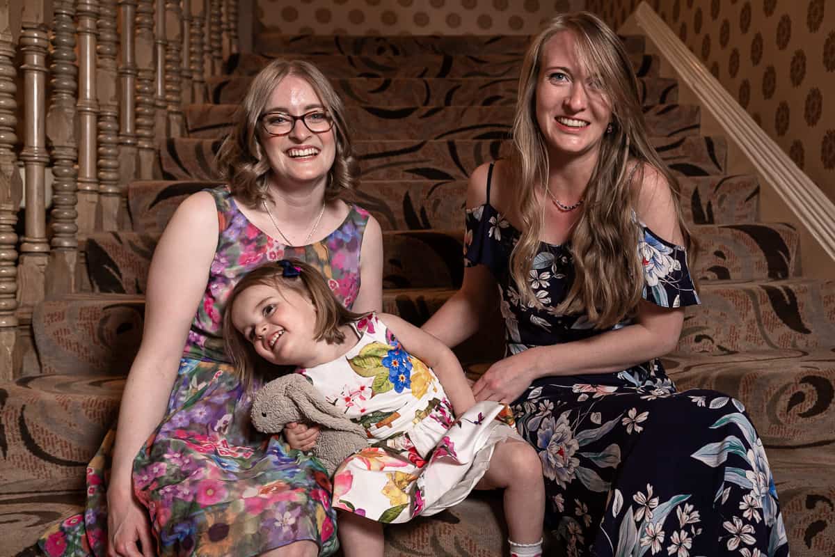 Two happy women tickling a little girl on the stairs of the Grosvenor Hotel in Chester, Cheshire